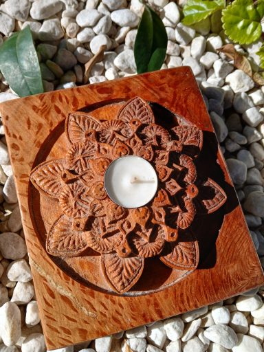 Portavelas de madera tallada en forma de flor con una vela blanca en el centro.