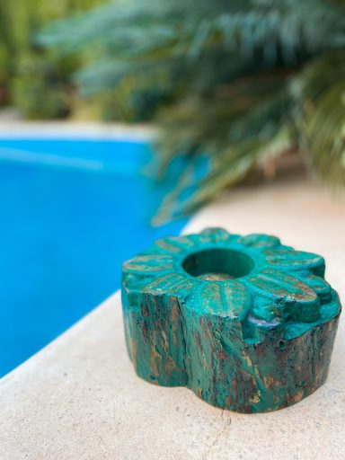 Soporte de vela de color verde con forma de flor, junto a una piscina.