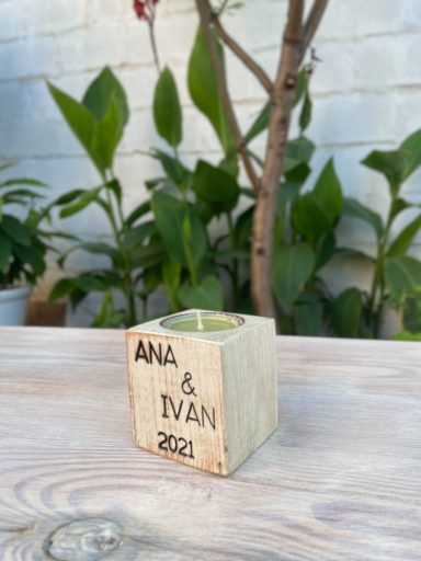 Vela en un recipiente cuadrado de madera con los nombres "Ana & Iván" y el año "2021".
